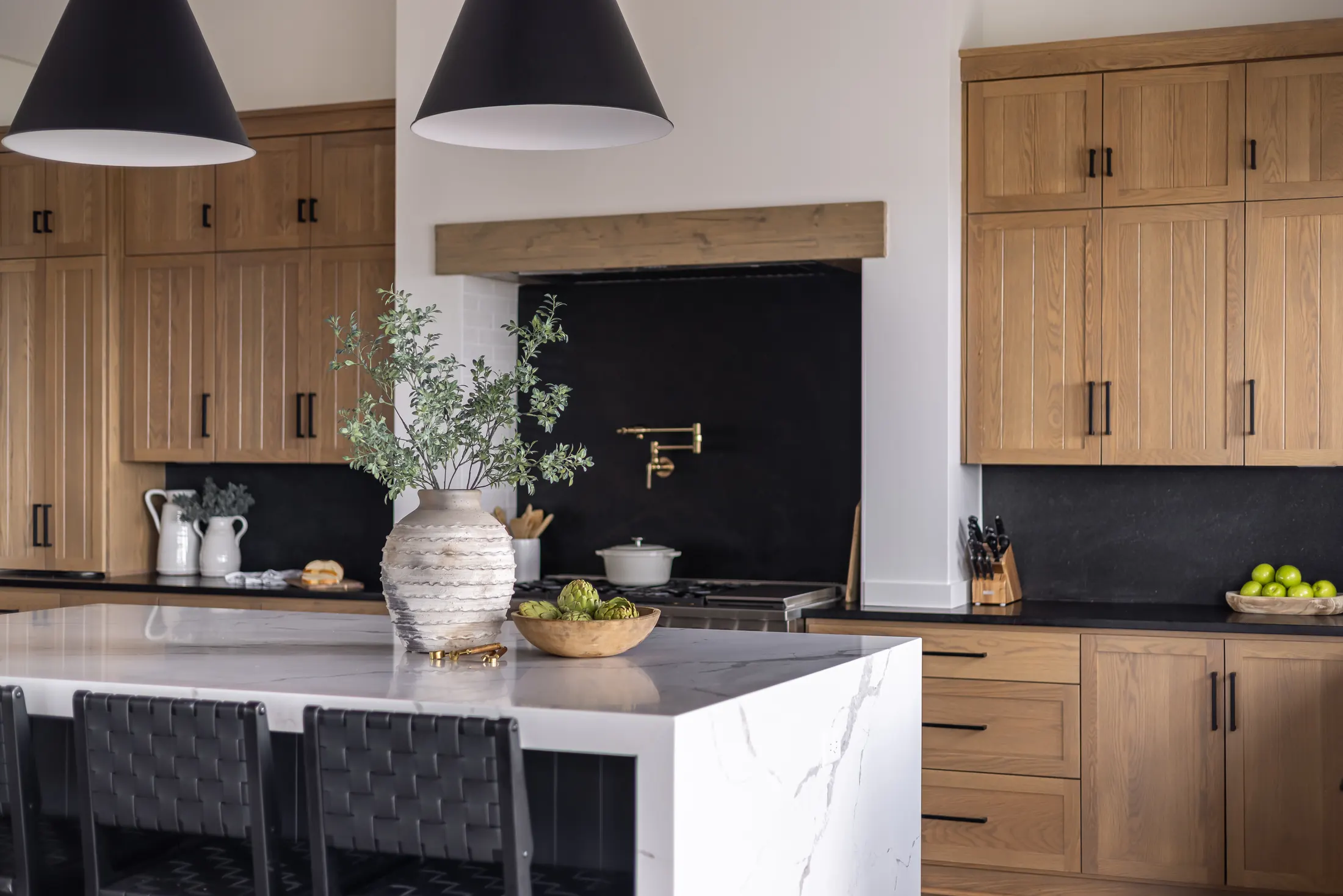 Kitchen with wood cabinets, a marble island and a brass pot filler