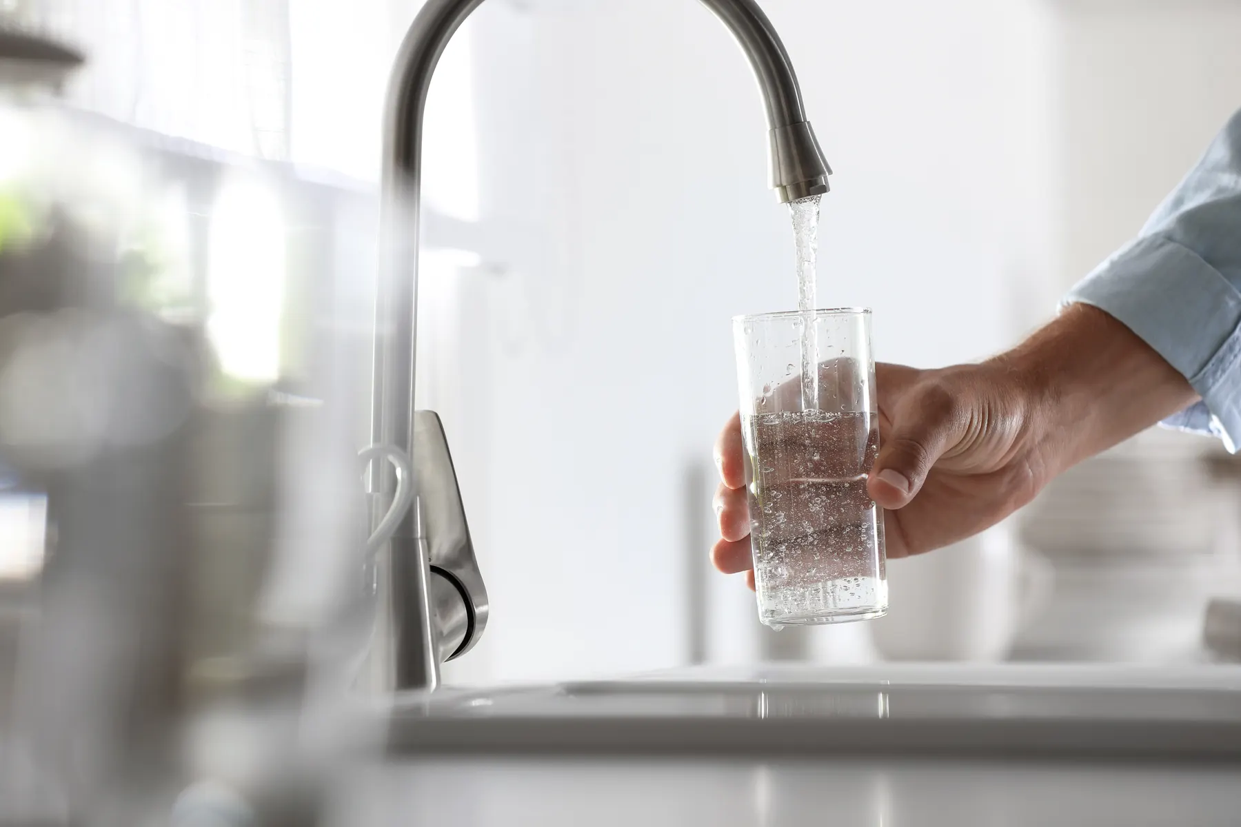 Glass of water held under a kitchen faucet