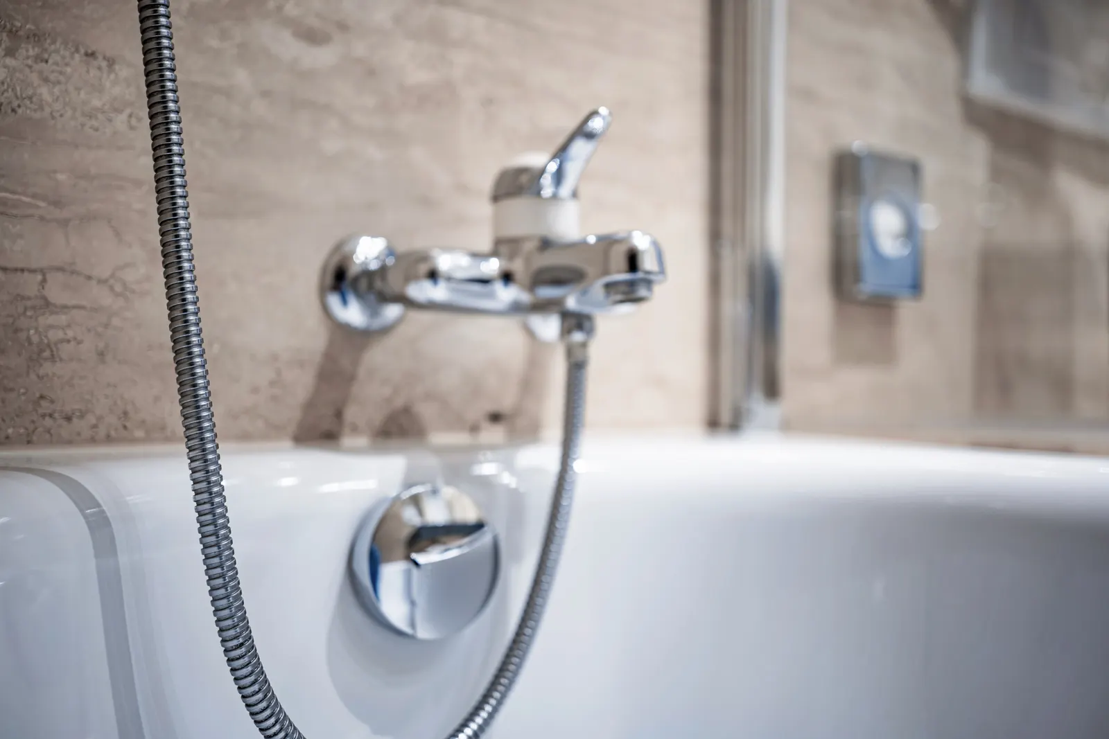 Chrome bath faucet and hand shower over a white tub
