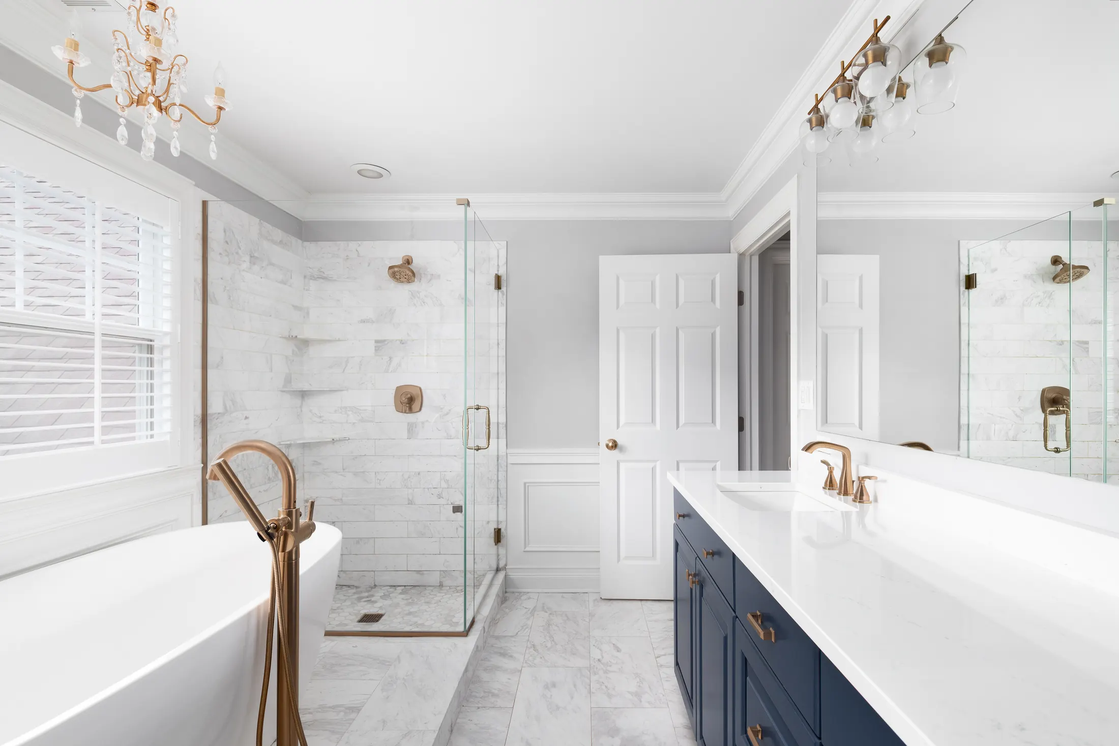 Bright bathroom with a freestanding tub, gold fixtures and a navy vanity