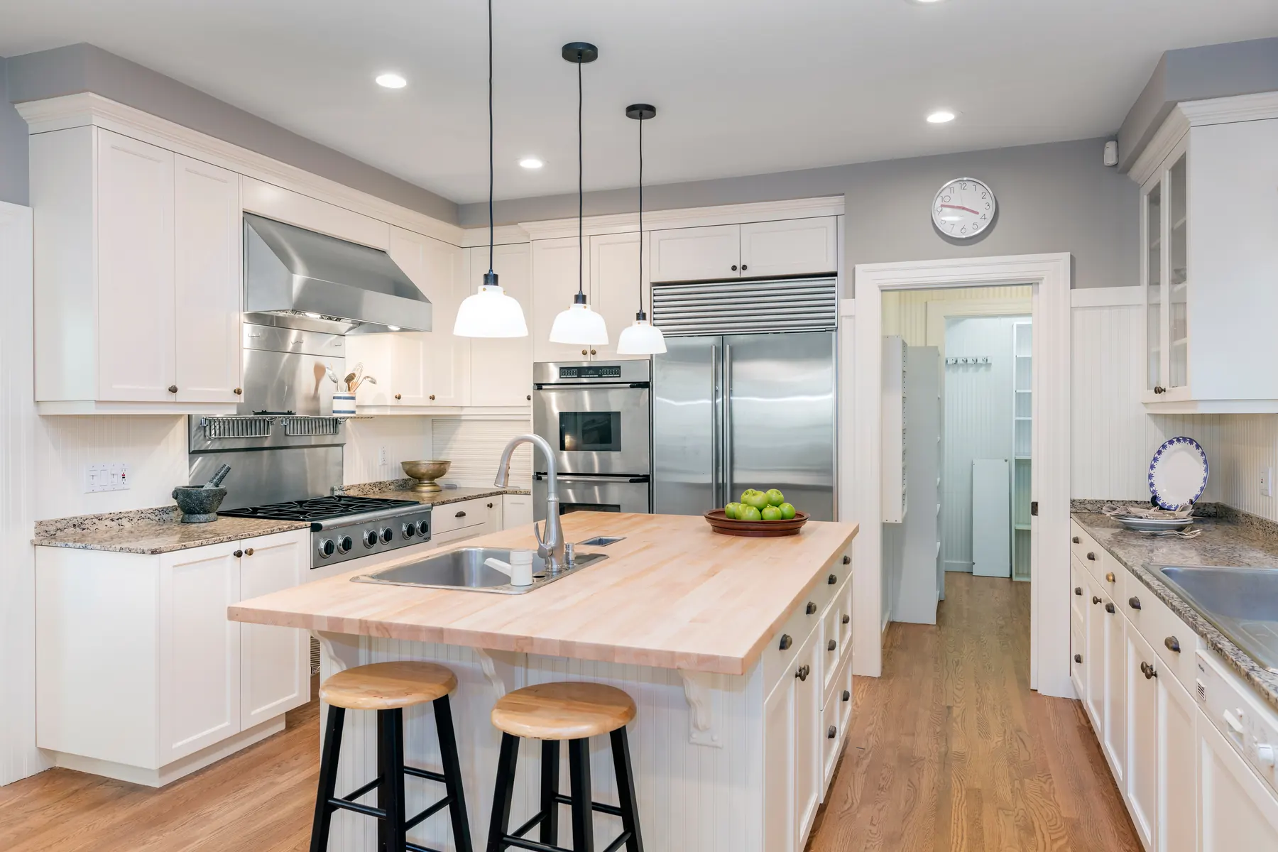 White kitchen with a butcher-block island and pendant lights